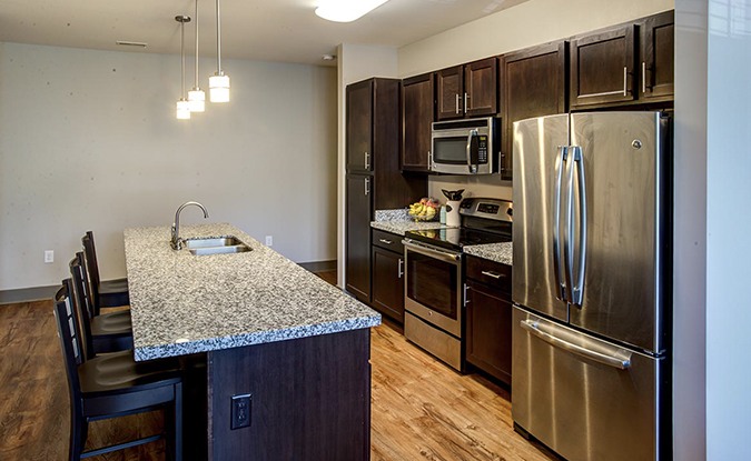 Apartment kitchen with island counter and silver appliances.